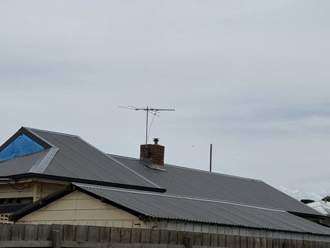 New corrugated roof on a bungalow, one gable still under a tarp